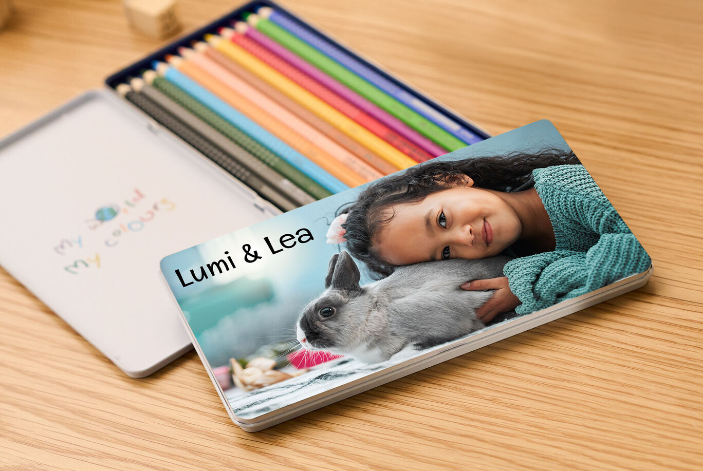 Une fille heureuse aux cheveux bouclés étreint un lapin gris sur une table.