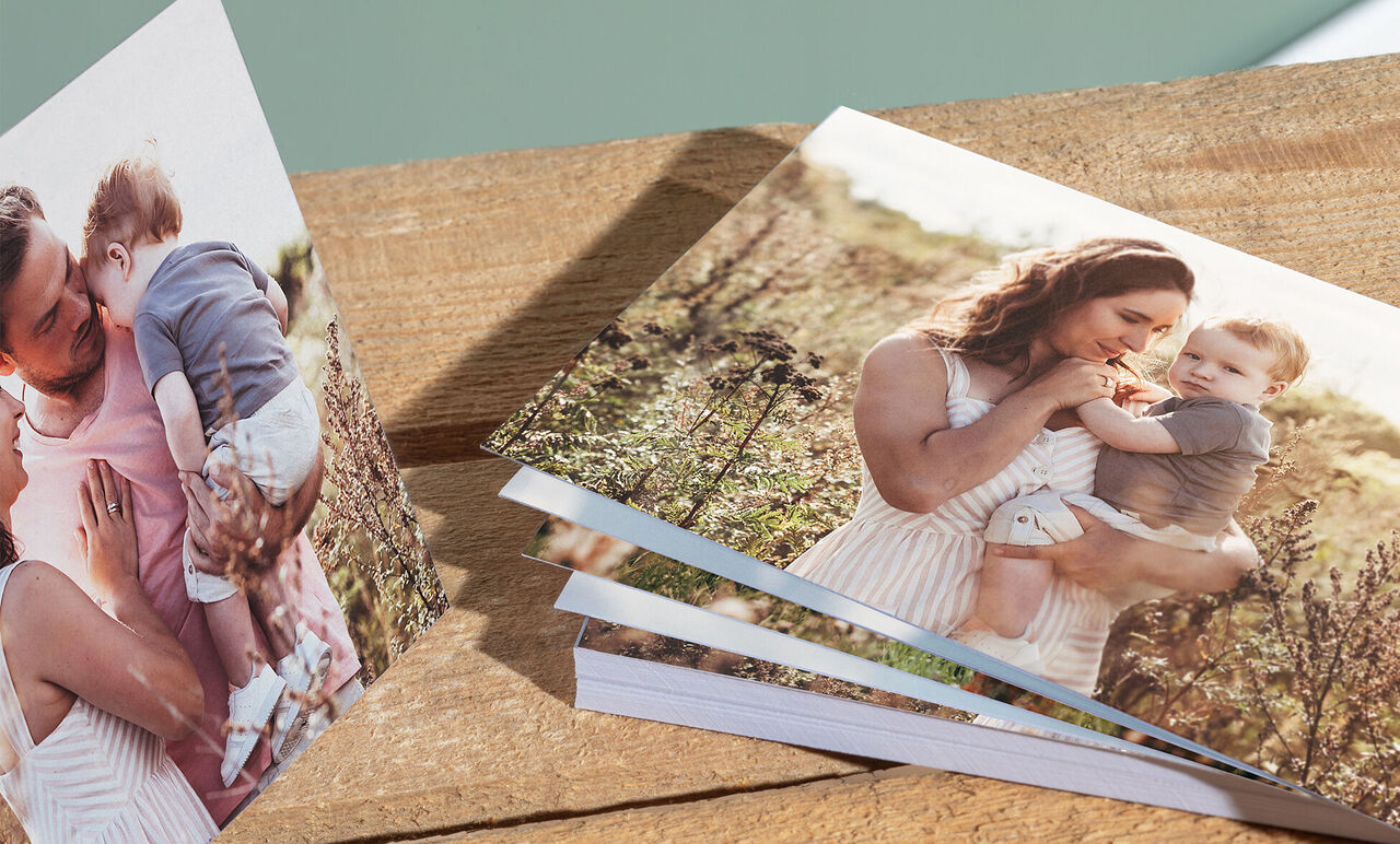 Un couple découvre un livre photo CEWE sur une surface en bois en plein air.