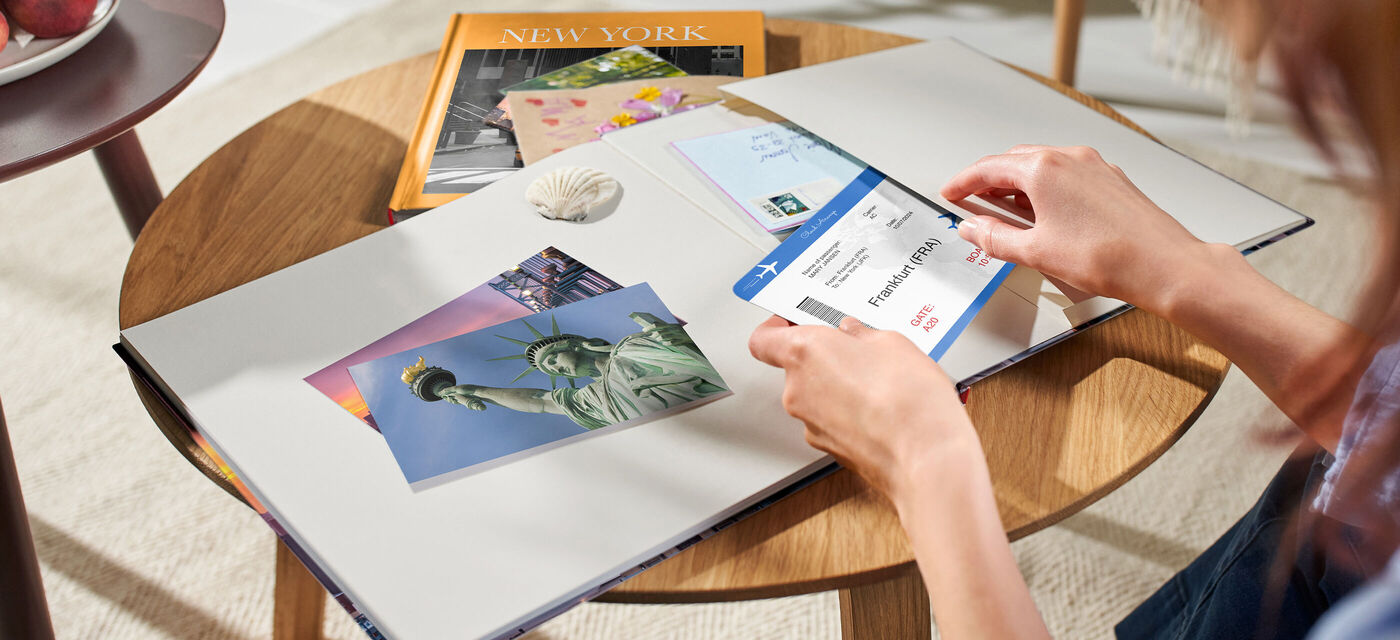 Une personne examine un album photo avec des souvenirs de New York, y compris une image de la statue de la liberté.