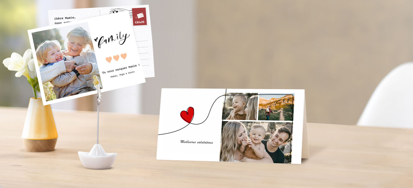 Deux cartes de vœux soigneusement conçues, une sur un support et une sur la table, avec photos et cœur rouge.
