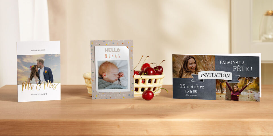 Trois exemples de design attrayants pour cartes CEWE sur une table en bois, entourées de cerises