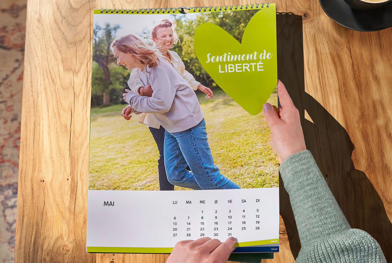 Deux personnes se tenant la main et souriant à l'extérieur, entourés de verdure, sur une page de calendrier.