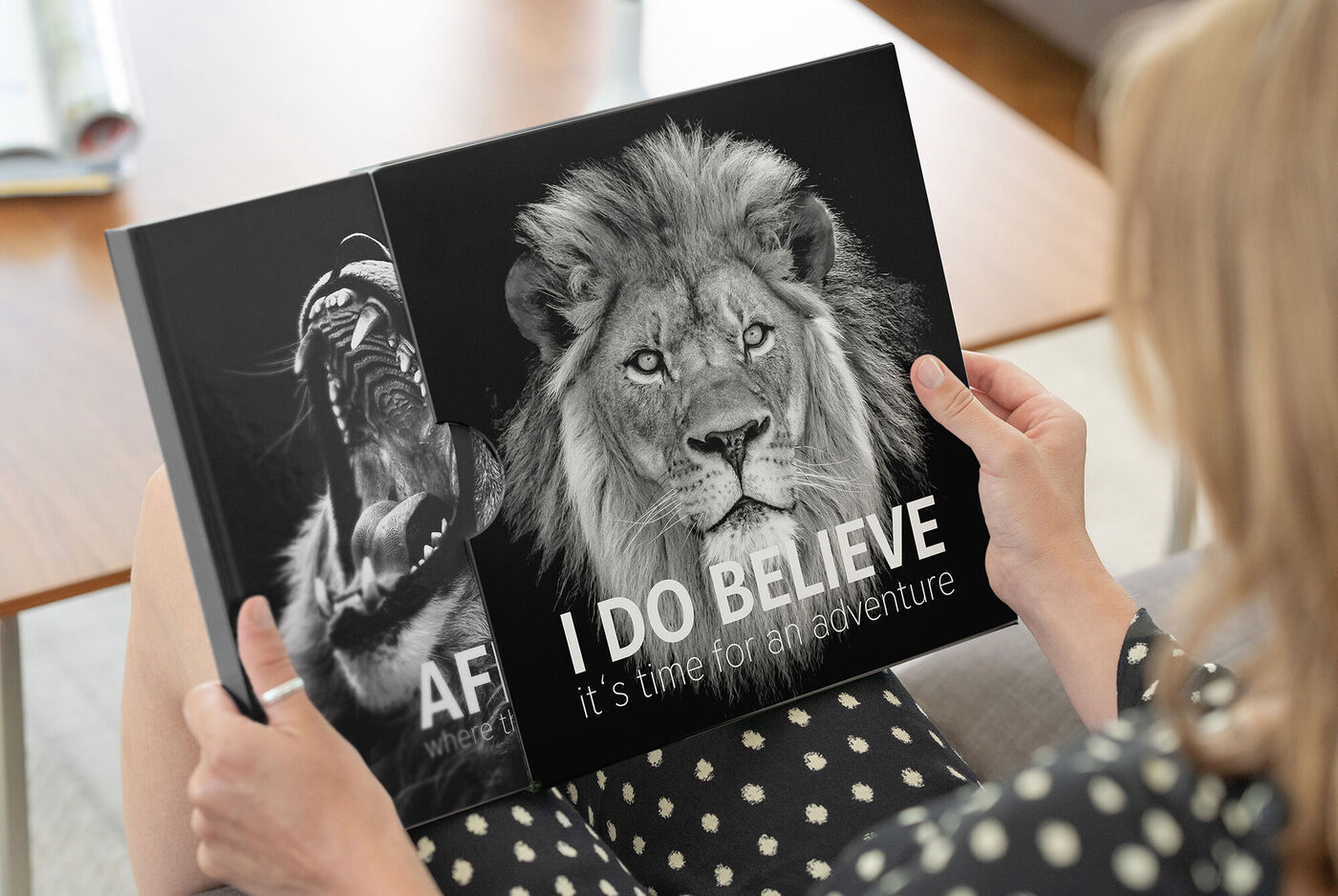 Une personne tient un CEWE ALBUM PHOTO avec des images de lions.