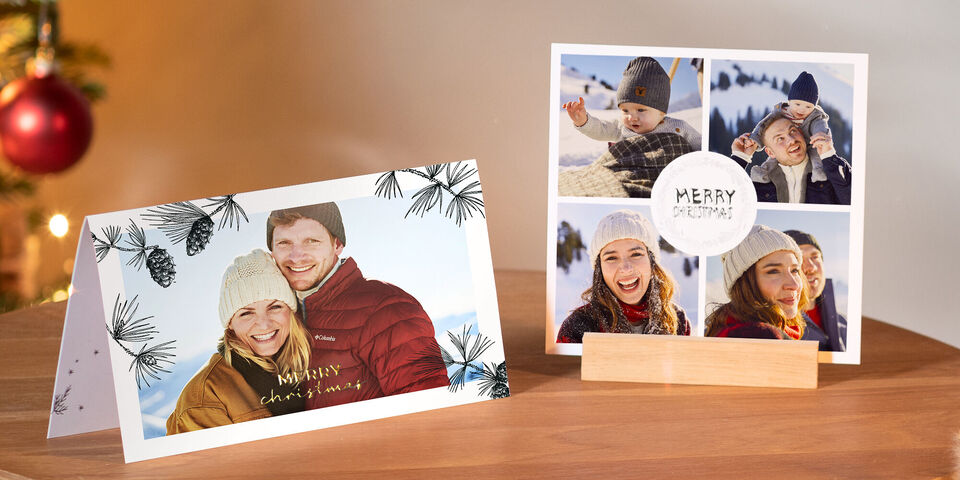 Deux cartes de Noël festives sur une table, l'une avec décoration hivernale et l'autre avec des photos de famille