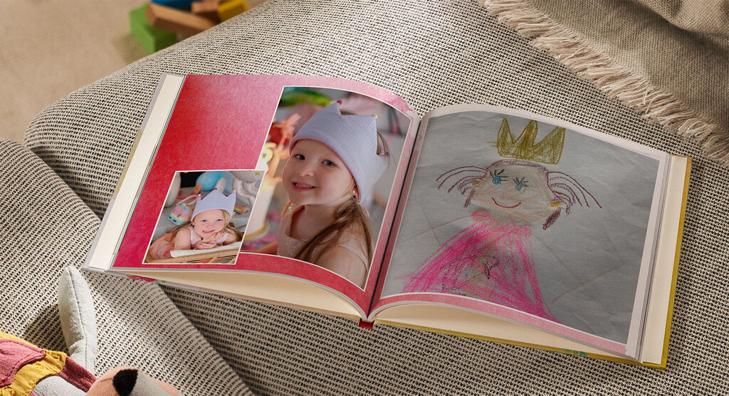 Un livre photo ouvert avec des pages colorées. Une figure dessinée à la main avec une couronne et une photo d'un enfant souriant. Le livre photo dégage joie et créativité.