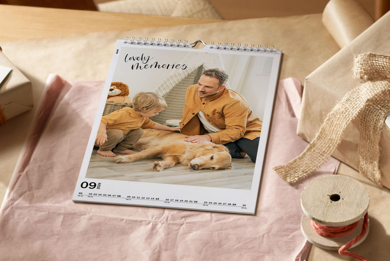 Un calendrier familial sur une table. Un enfant et un chien sont dessus, avec un adulte à leurs côtés. Le mois est septembre.