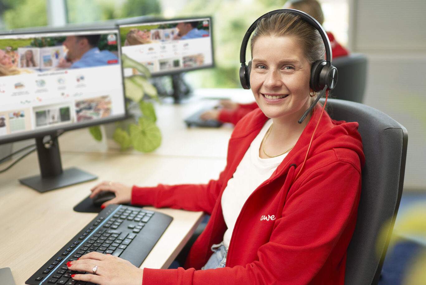 Une employée de CEWE travaille sur l'ordinateur avec un casque pour aider les clients.